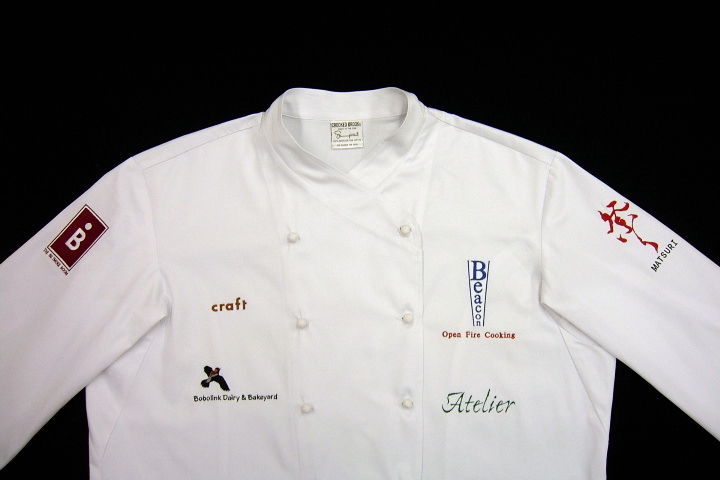 Chef Coat (Jacket) Style CBM101: Shown in white gabardine with white gabardine ball buttons. Embroidered with logos of the following New York City restaurants; Atelier, Beacon,The Biltmore Room, Craft, and Matsuri.