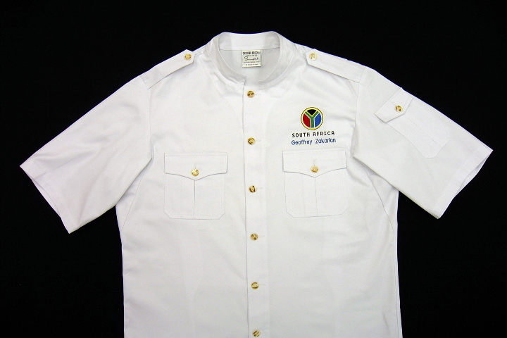 Safari Style CBM104: Shown in white gabardine, with squared collar, short sleeves, inverted pleat chest pockets with flaps, inverted pleat left shoulder-sleeve pocket with flap, epaulettes, river-shell buttons, and back pleats (not shown).
