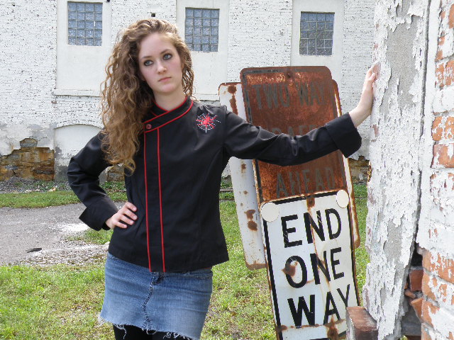 Cropped Women's Jacket Style CBW105H; Shown in black 100% cotton Supima Gabardine with two rows of Foxy Red piping along the collar and placket, one red tagua nut top button, spider embroidery on left front shoulder and square cuffs.