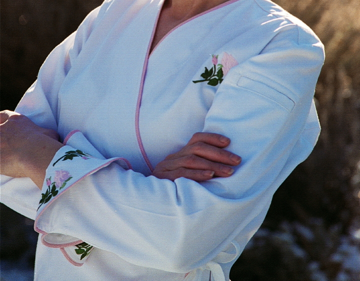 Close-up image of rose embroidery on cuffs, and left chest, of Women's Chef Coat Style BSW106: Shown in White, 100% cotton gabardine, Pink Sham piping (cuffs, collar & front), left sleeve tailored welt pocket & Rose embroidery (3 on each cuff & one on the left chest).