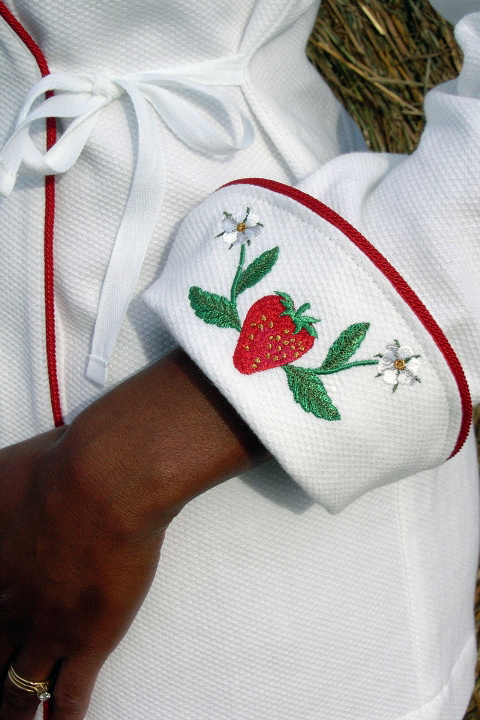 Women's Chef Coat Style BSW106: Shown in White, 100% cotton petti point pique, red berry piping (cuffs, collar & front), & strawberries & flowers embroidery (one on each cuff).Women's Chef Coat Style BSW106: Shown in White, 100% cotton petit point pique, red berry piping (cuffs, collar & front), & strawberries & flowers embroidery (one on each cuff).