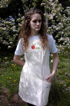 Women's Bib apron style W740; Shown in Natural, 100% cotton riptstop with two side hip tailored welt pockets, pink sham piping on pocket welts & along princess seams, embroidered apple botanical on center chest & embroidered apple blossom chains; one on each pocket.