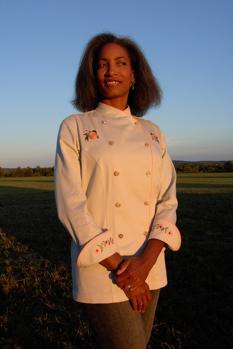 Women's Chef Coat Style BSW101: Shown in Ivory, 100% cotton Denim, bisque piping (collar, front & cuffs), Peach botanicals (one embroidered on each chest), peach blossom chains (one embroidered on each cuff) & awabi buttons.