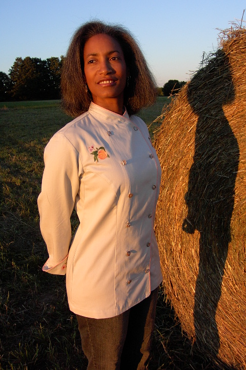 Women's Chef Coat Style BSW101: Shown in Ivory, 100% cotton Denim, bisque piping (collar, front & cuffs), Peach botanicals (one embroidered on each chest), peach blossom chains (one embroidered on each cuff) & awabi buttons.