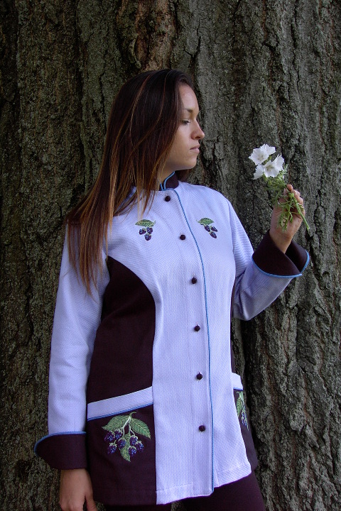 Women's Chef Coat style BSW104; Shown in Lavender & black, 100% cotton petti point pique & 100% cotton Gabardine, two front hip tailored welt pockets, Copen piping (collar, front, cuffs & pockets), Black Gabardine, hand tied knot buttons & blackberry embroideries on the chests, pockets, & back of collar.