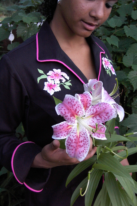 Women's Chef Coat Style BSW109: Shown in Black, 100% cotton gabardine, ruby glint piping (collar, cuffs & front), stargazer lily embroidery (One on each chest) & faux mother-of-pearl buttons.