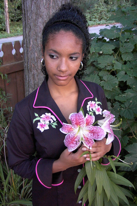 Women's Chef Coat Style BSW109: Shown in Black, 100% cotton gabardine, ruby glint piping (collar, cuffs & front), stargazer lily embroidery (One on each chest) & faux mother-of-pearl buttons.