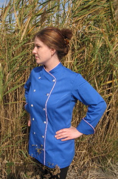 Women's Chef Coat Style BSW101: Shown in blue, certified 100% organic cotton twill, pink sham piping (collar, cuffs, & both fronts), left sleeve tailored welt pocket & pink troca buttons.